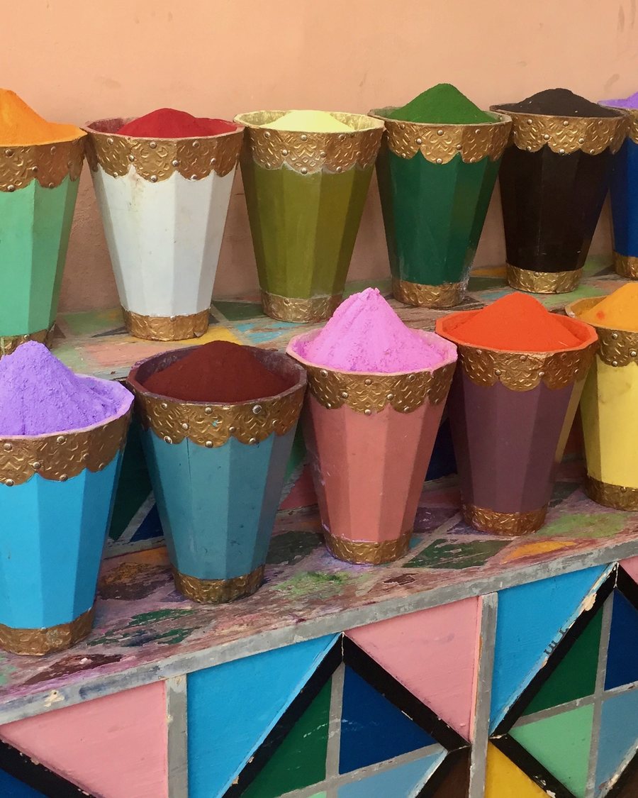 Rows of brass-rimmed jars filled with brightly colored pigment powders