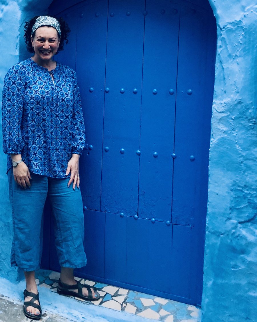 Nicole standing beside a deep blue studded door in the Chefchaouen medina